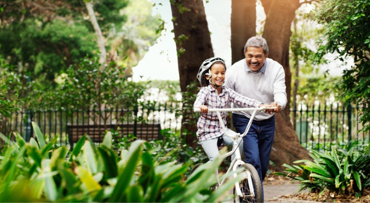 A man who's semi-retired teaches his granddaughter how to ride a bicycle.